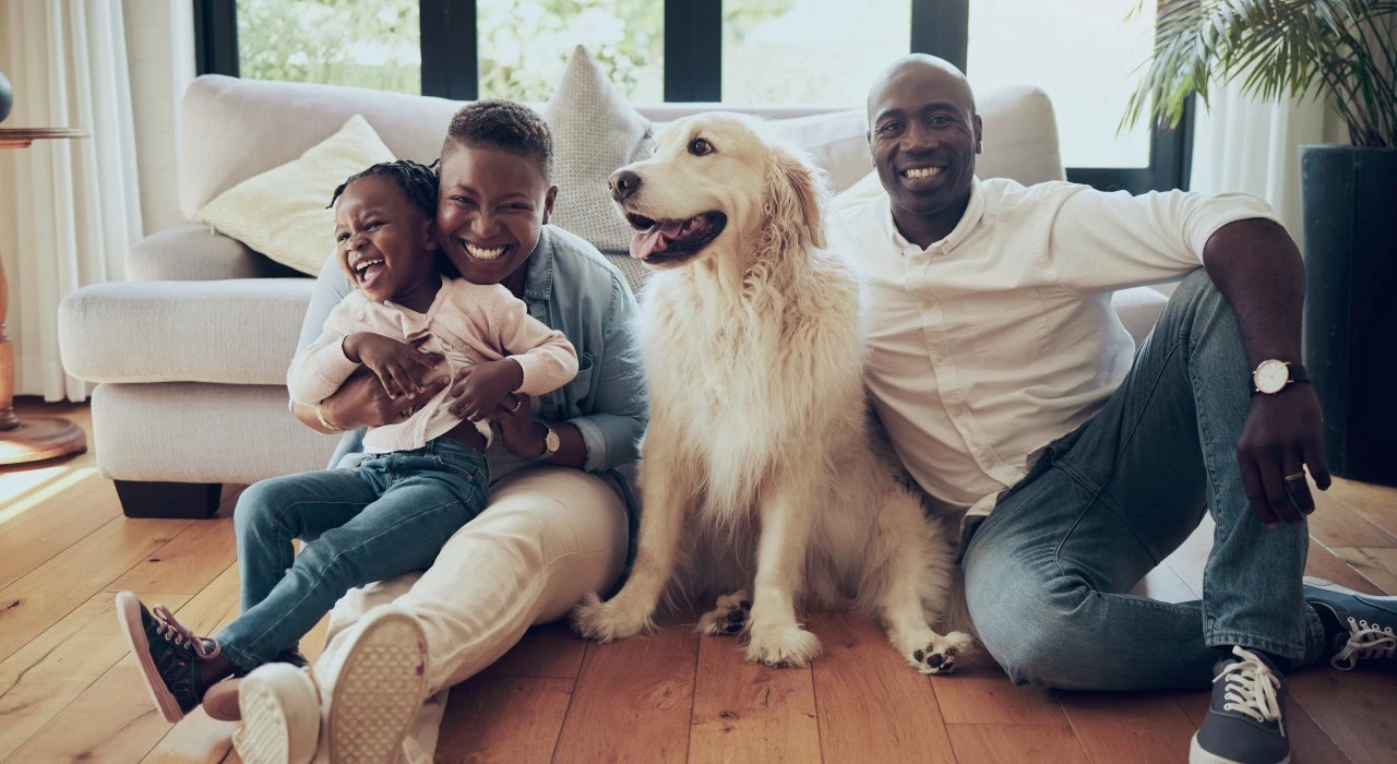 Happy Couple with child and dog sitting on floor in living room