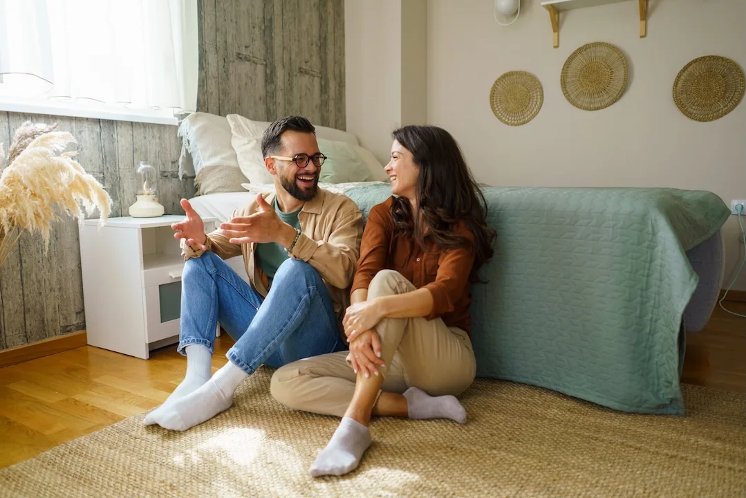 Couple chatting on a bedroom floor.