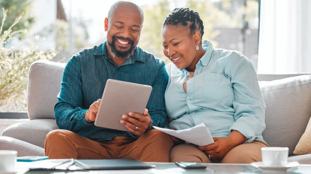 Mature couple looking through their bills while using a digital tablet