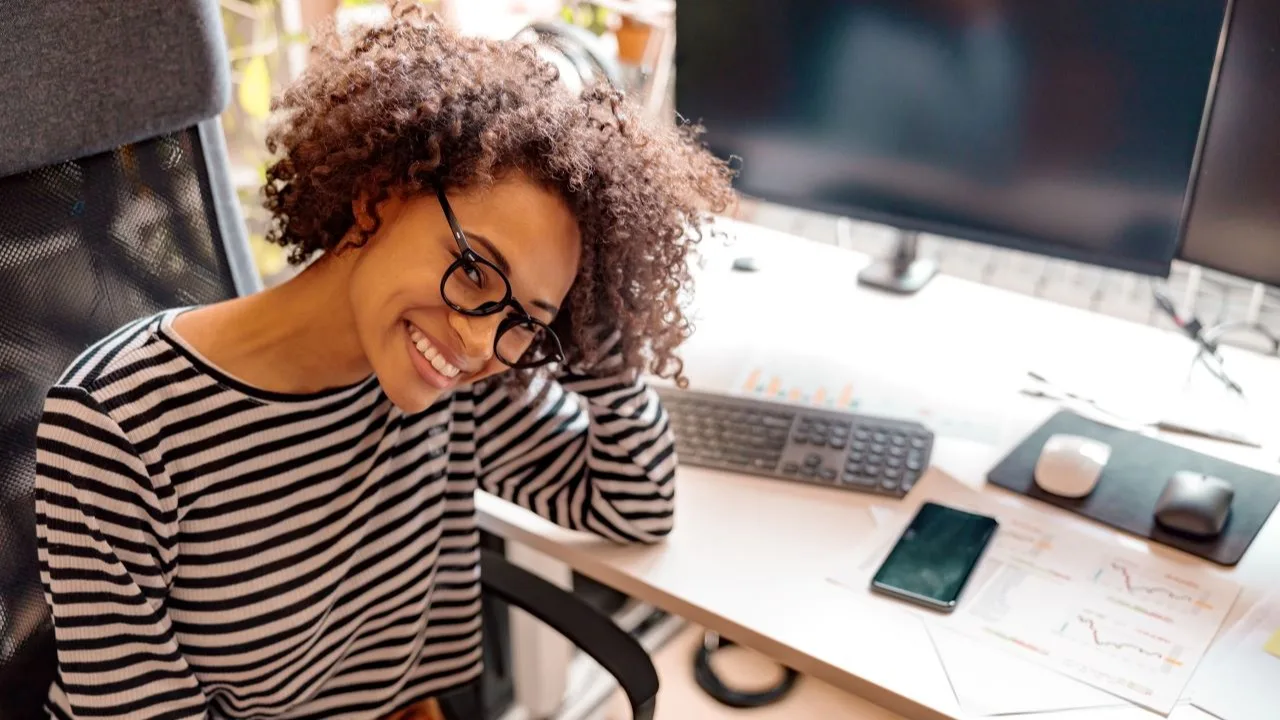 Young woman sitting at desk, smiling after crushing her debt