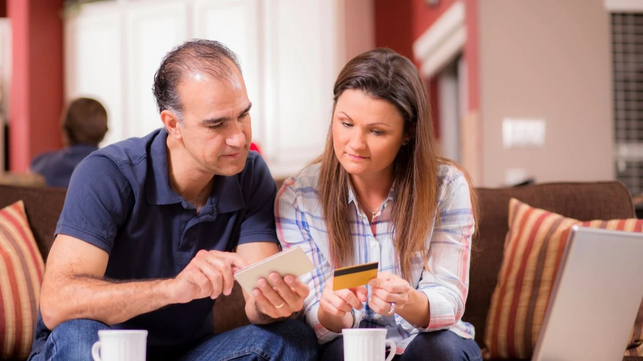 Middle age couple work together to figure out how to pay their monthly bills. 