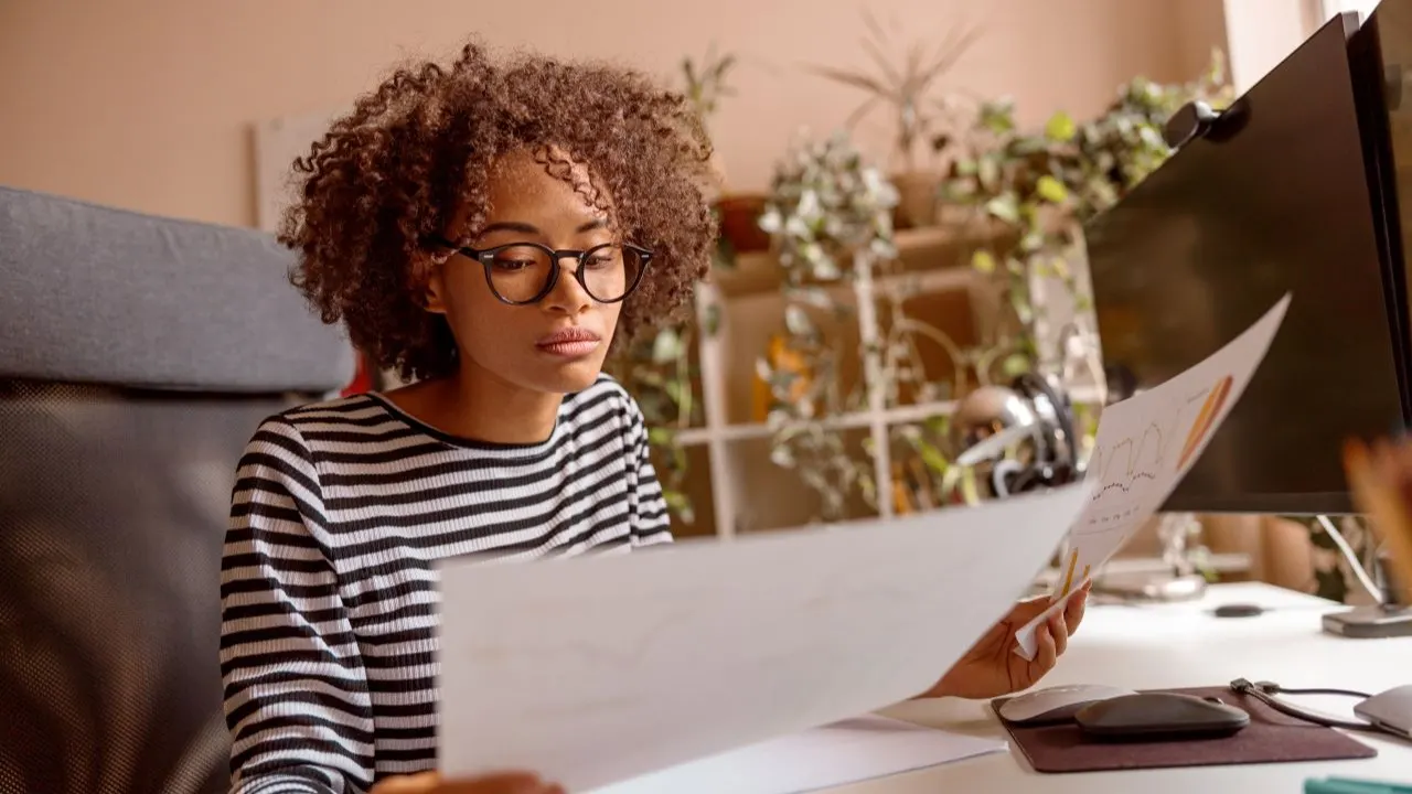 young woman adult sitting at the table and analyzing debts deciding between debt consolidation and debt relief