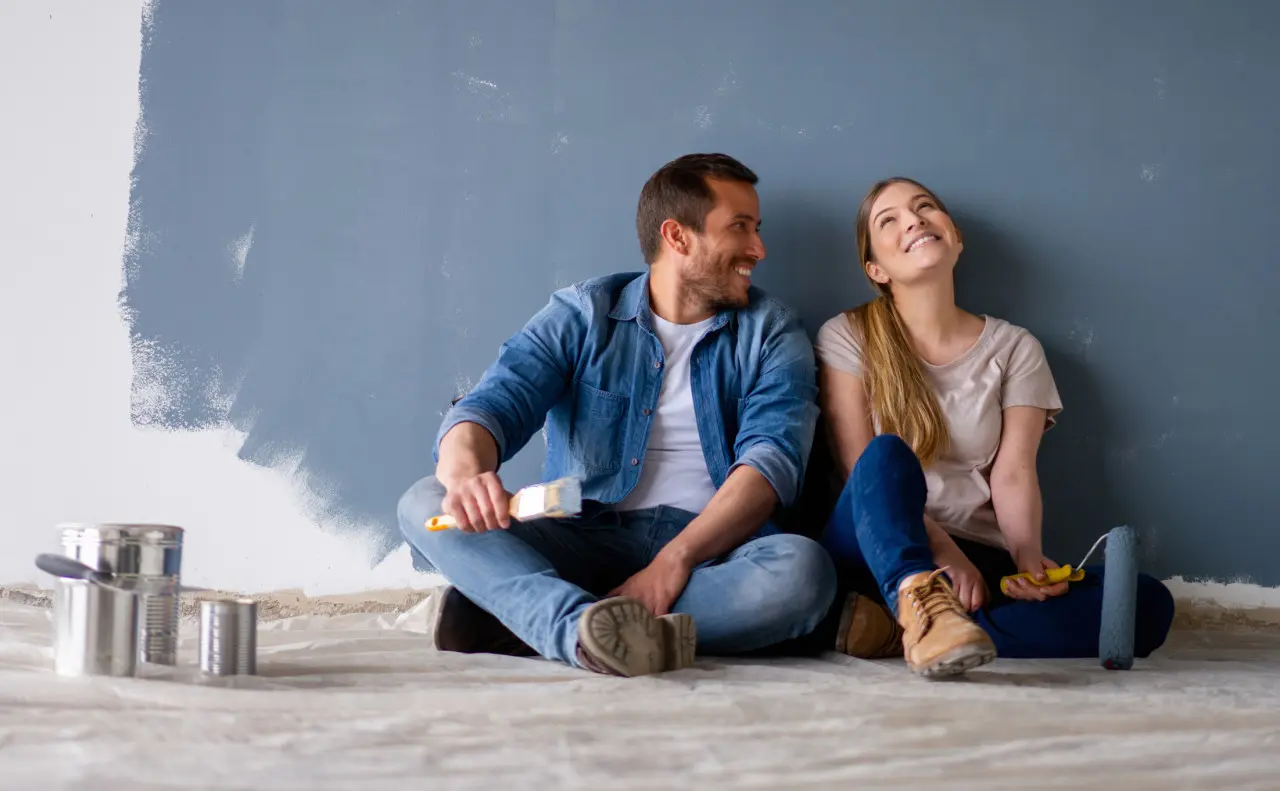 Loving couple having fun renovating their house and painting the walls and smiling while taking a break