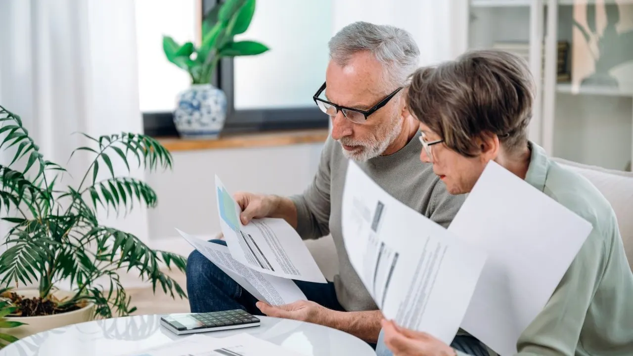 Elderly couple checking documents, credit reports and discussing budget.