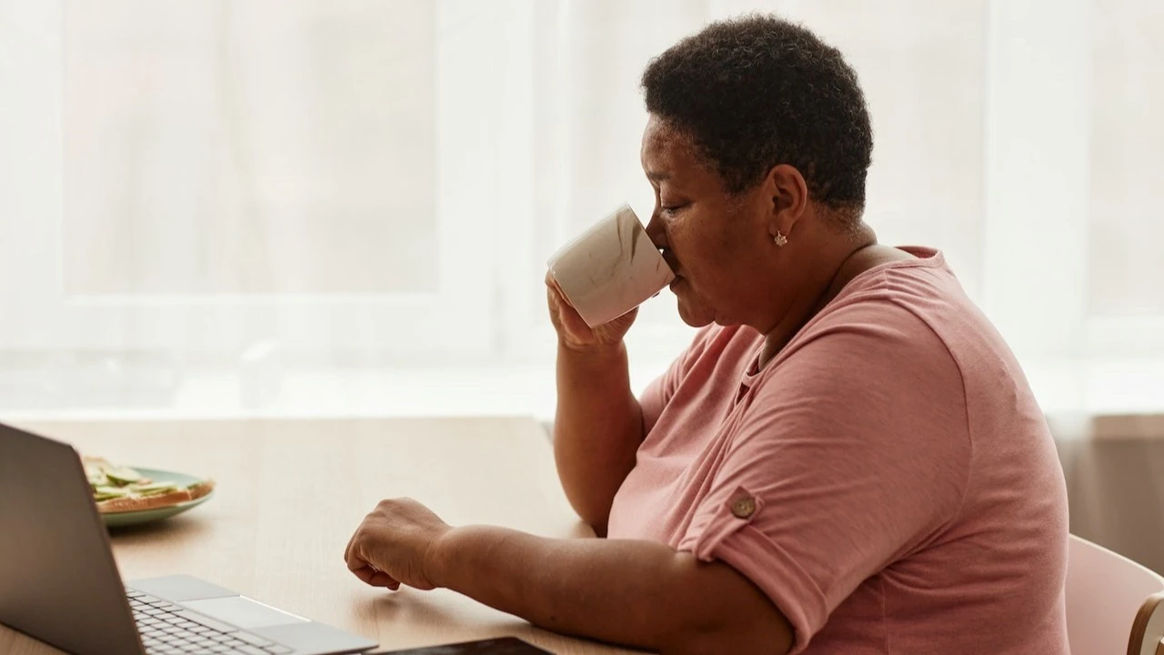 Woman drinking coffee and looking at her computer