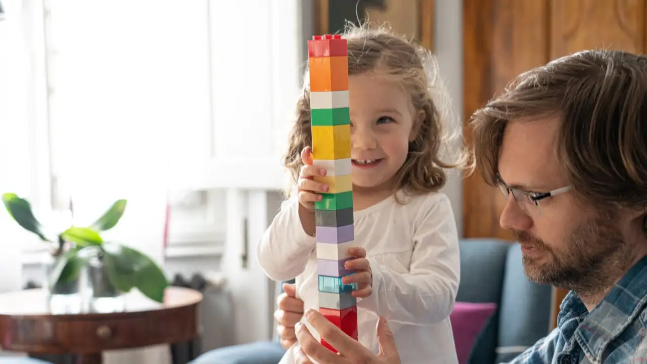 Father and daughter playing together with colored building blocks