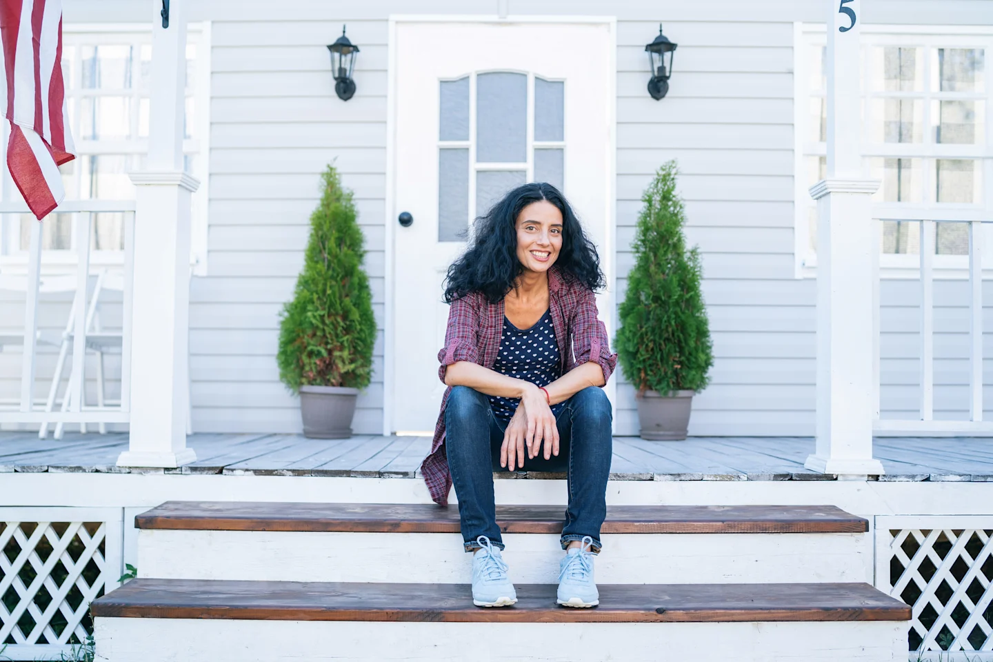 Smiling woman sits on her front porch. 