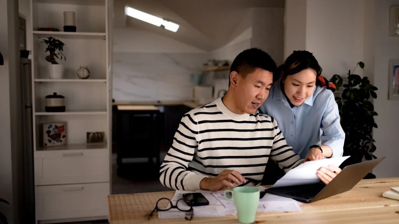 Young couple cooperating while going through their bills at home.
