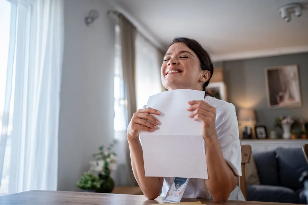 Woman reading paperwork looks happy.