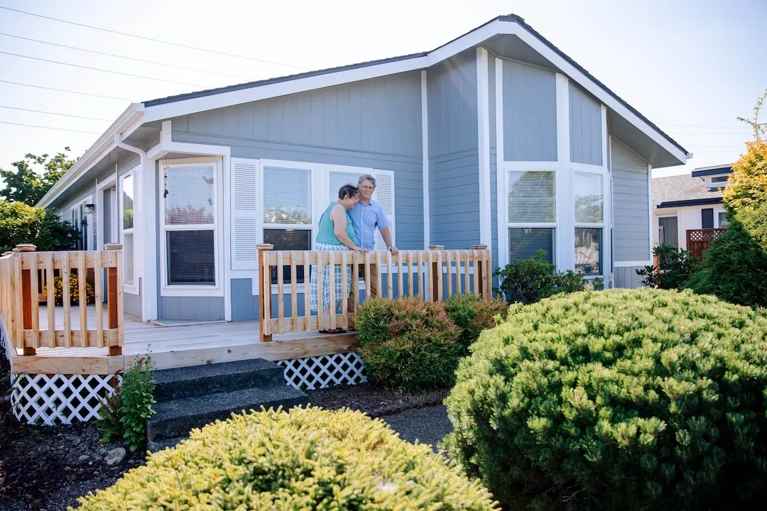Older couple standing on the deck of their mobile home.