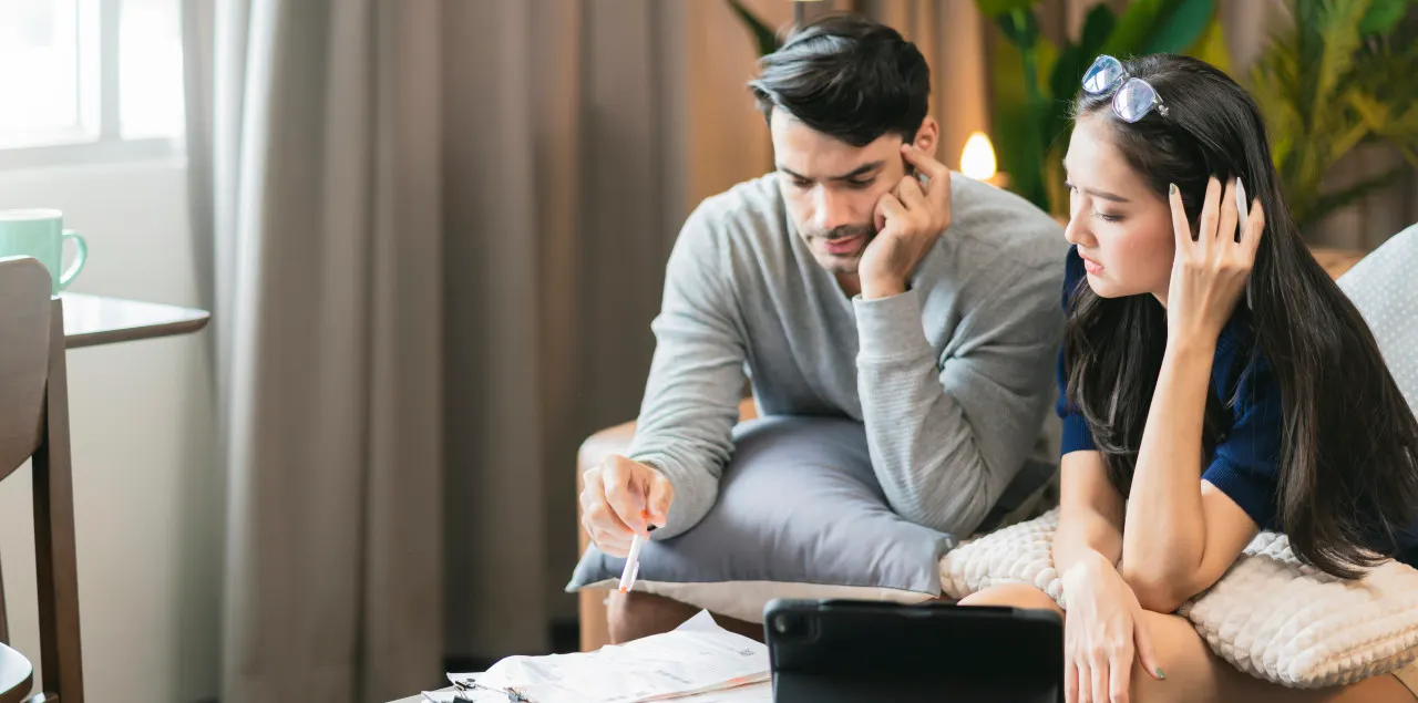 husband and wife discussing mortgage offer ogether with confused look - home interior background