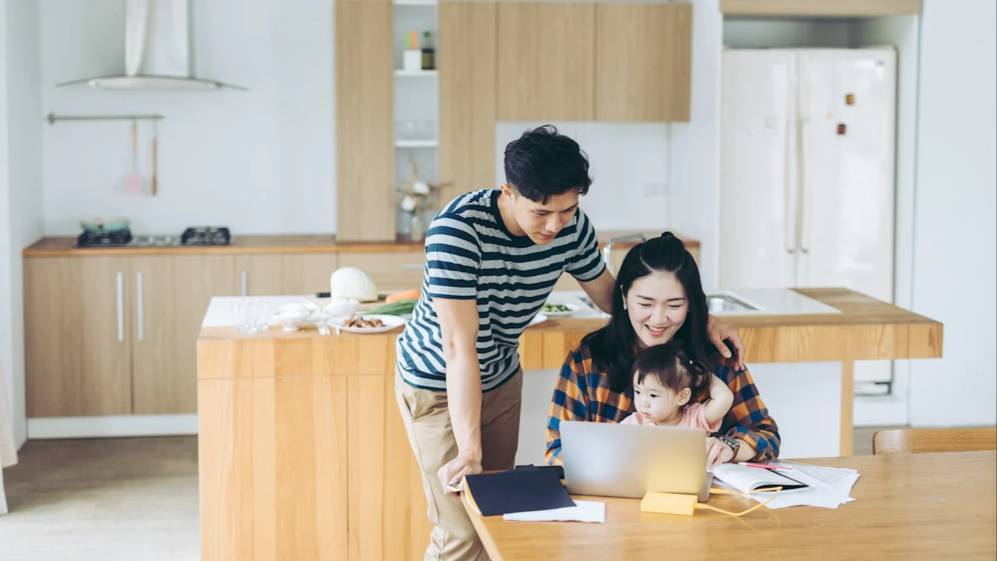 Young couple in kitchen with child searching for a $10000 personal loan