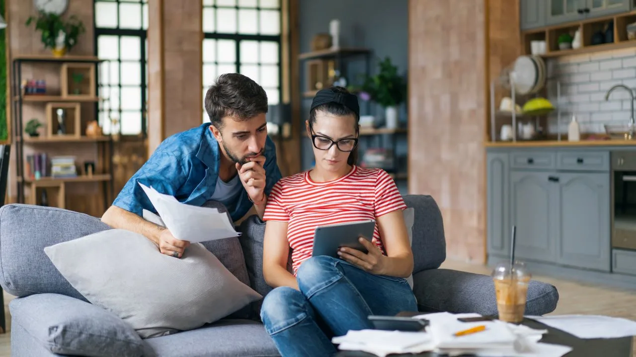 Couple calculating healthcare bills at home using laptop and calculator