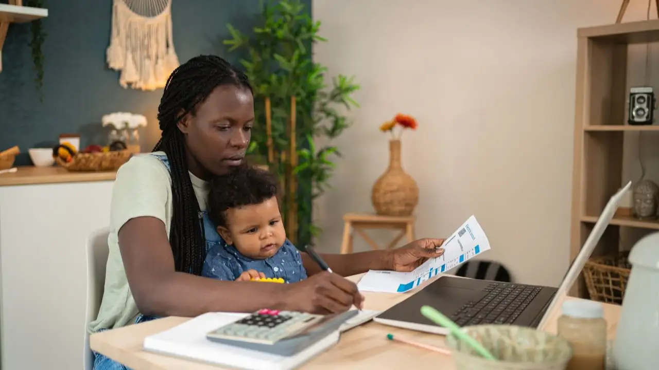 Single mother analyzing and calculating her home finances, while her baby boy sitting in her lap