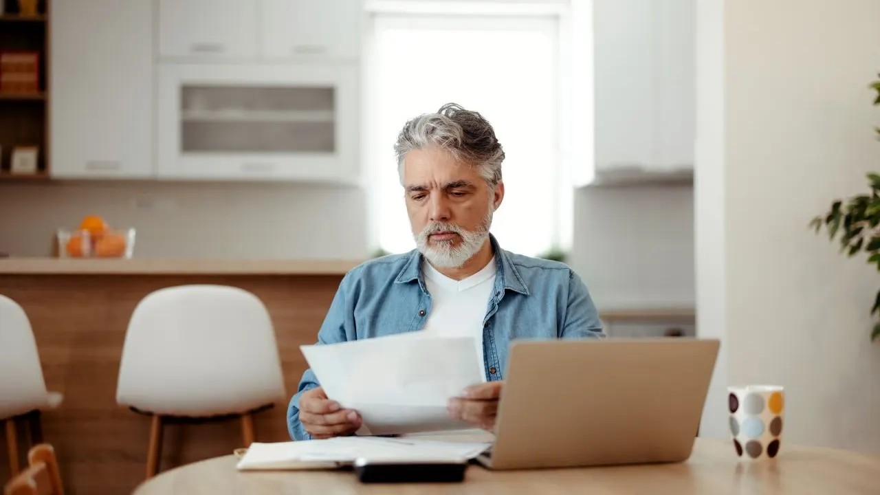 Man sitting around dining table and reviewing mortgage deed and lien documents