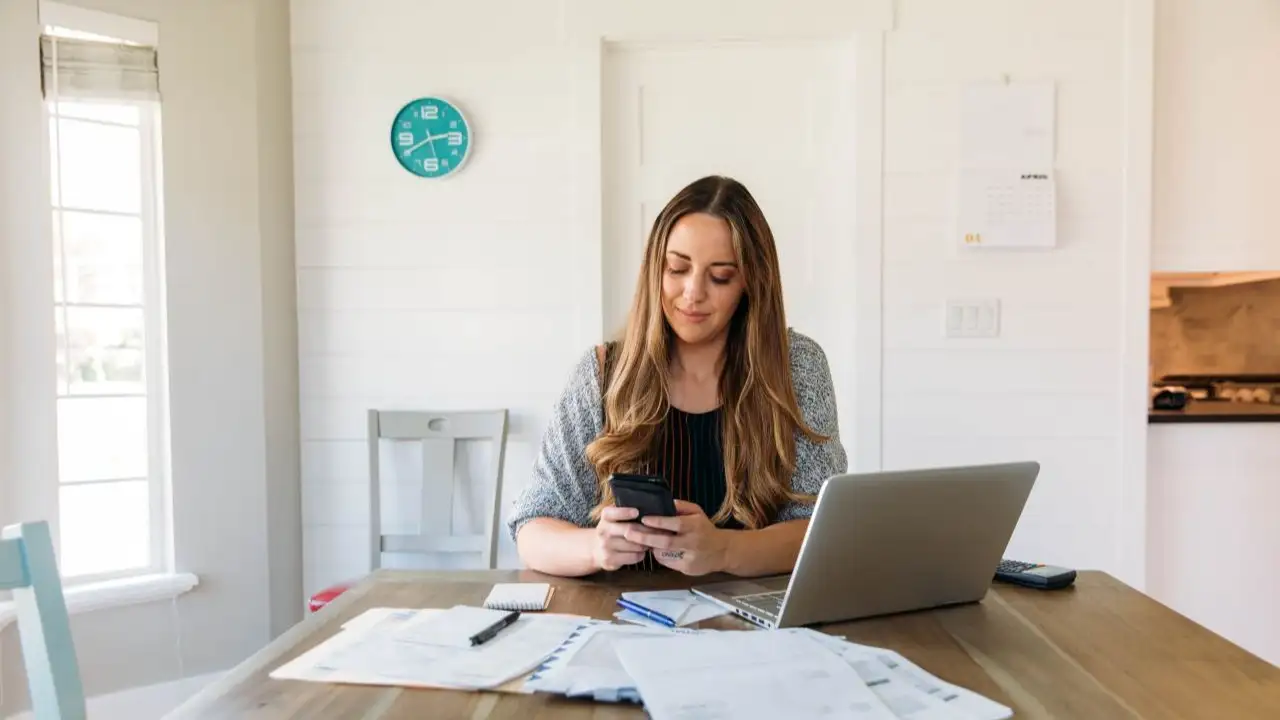 Woman managing finances at home, reviewing bills and weighing whether to focus on credit or paying off debt.