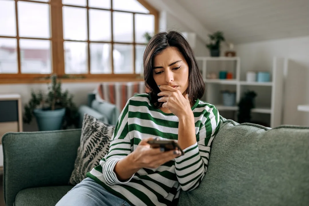Woman concernedly looks at smartphone