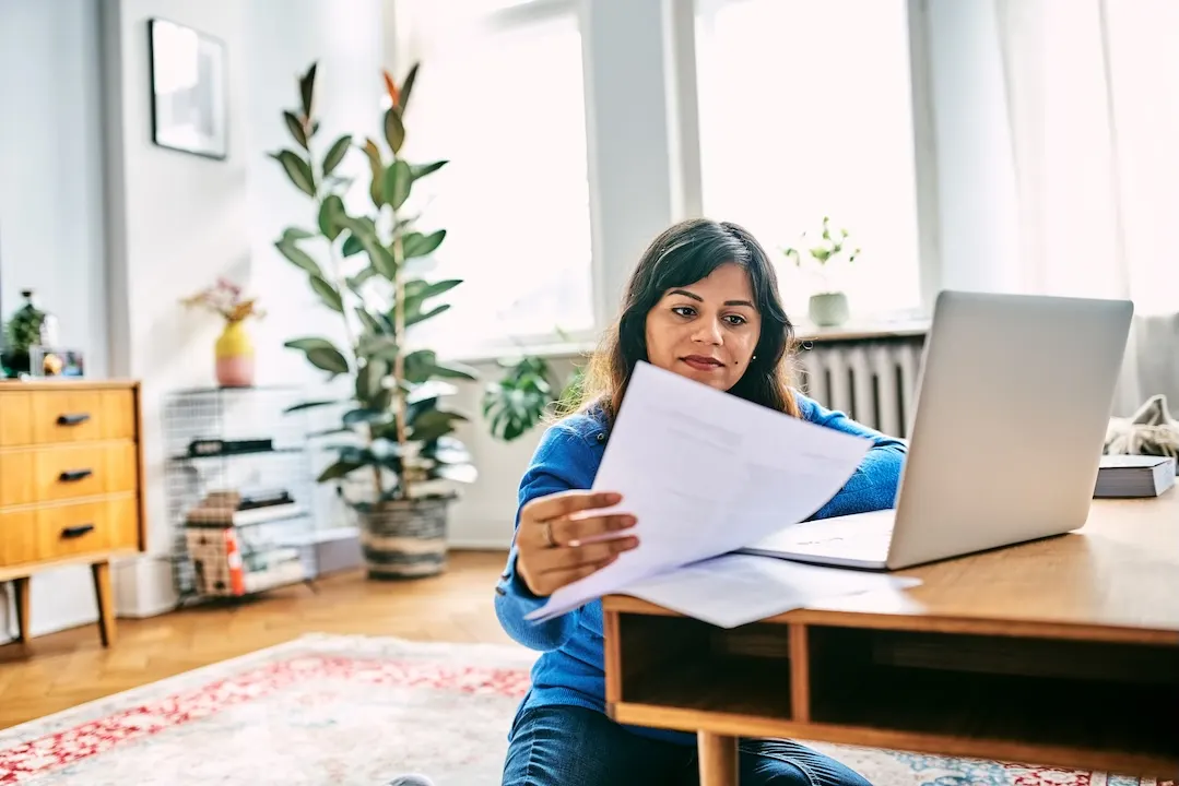 Woman reviewing paperwork while sitting at a coffee table.